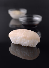 Nigiri sushi with white fish resting on reflective black surface