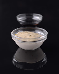 Creamy sauce with herbs and soy sauce reflecting on dark background