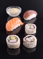 Delicious sushi rolls with salmon and tuna nigiri and soy sauce on black reflective surface
