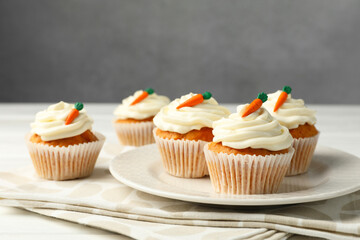 Tasty carrot muffins with cream on white wooden table, closeup