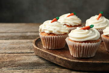 Delicious carrot cupcakes on wooden table against grey background, closeup. Space for text