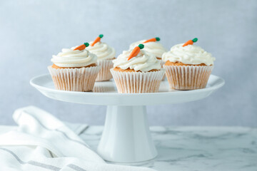 Delicious carrot cupcakes on white marble table against grey background, closeup