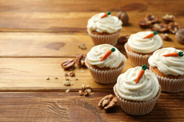 Delicious carrot cupcakes and walnuts on wooden table, closeup. Space for text