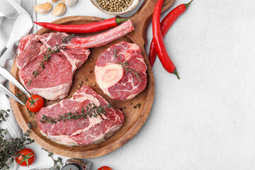 Pieces of raw beef, spices and products on light grey table, flat lay. Space for text