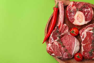 Pieces of raw beef, spices and products on green table, top view. Space for text