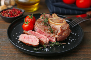 Pieces of delicious beef meat, spices and tomatoes on wooden table, closeup