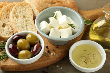 Delicious marinated olives, bread and feta cheese served on wooden table, closeup