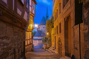 Illuminated fachwerk house in the old town of Marburg Germany with narrow alley and evening light
