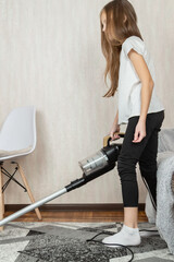 Little girl using vacuum cleaner in room