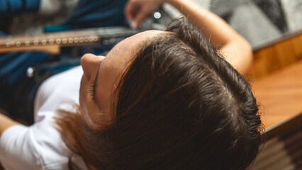 From above Young caucasian brunette woman sitting on floor and playing electric guitar at home