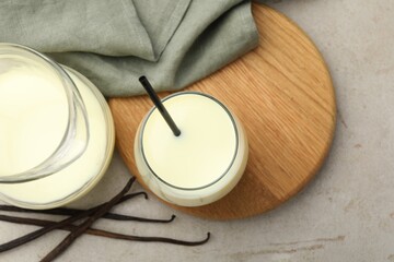 Delicious vanilla milk and pods on grey table, flat lay