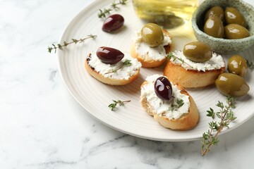 Delicious sandwiches with cream cheese and marinated olives on white marble table