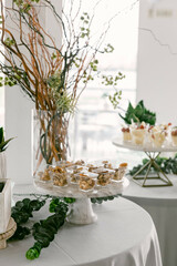 Elegant dessert display with floral decorations at a modern event venue during daytime
