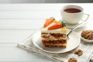 Piece of delicious homemade carrot cake served on white wooden table, space for text
