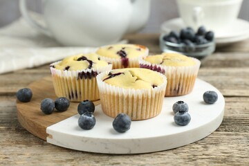 Delicious muffins with blueberries on wooden table, closeup