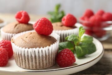 Delicious muffins with raspberries and mint on wooden table, closeup