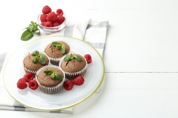 Delicious muffins with raspberries and mint on white wooden table. Space for text