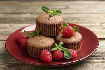 Delicious muffins with raspberries and mint on wooden table, closeup