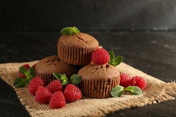 Delicious muffins with raspberries and mint on dark textured table, closeup