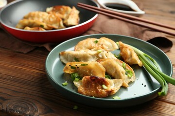 Tasty fried gyoza (dumplings) on wooden table, closeup