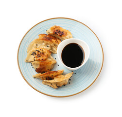 Tasty fried gyoza (dumplings) and soy sauce isolated on white, top view