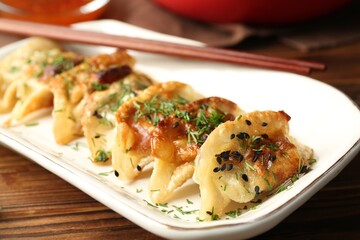 Tasty fried gyoza (dumpling) on wooden table, closeup