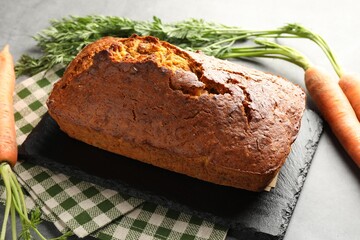 Tasty carrot cake and vegetables on grey textured table, closeup