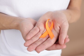 Multiple Sclerosis awareness. Man with orange ribbon on brown background, closeup