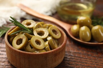 Delicious marinated olive rings and rosemary in bowl on wooden table, closeup