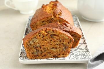 Cut homemade carrot cake with nuts on light grey table, closeup