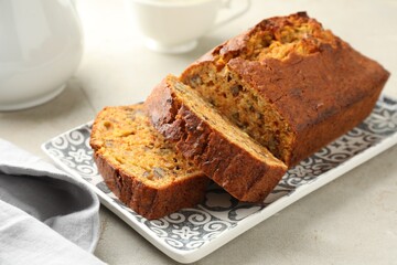 Cut homemade carrot cake with nuts on light grey table, closeup