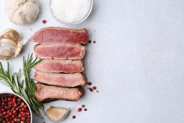 Delicious sliced beef tenderloin with different degrees of doneness and spices on light table, flat lay. Space for text
