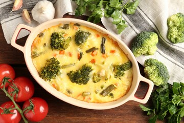 Delicious vegetable casserole and ingredients on wooden table, flat lay