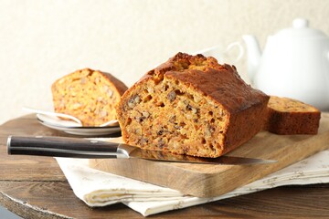 Cut homemade carrot cake with nuts and knife on wooden table, closeup