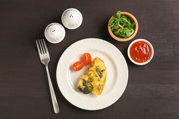 Tasty vegetable casserole served on black wooden table, flat lay