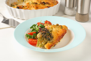 Tasty vegetable casserole and salad on white wooden table, closeup