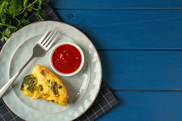 Piece of tasty vegetable casserole and sauce on blue wooden table, top view. Space for text