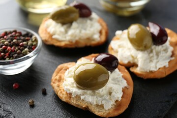 Delicious sandwiches with marinated olives, cream cheese and peppercorns on dark table, closeup