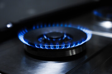 Gas burner with blue flame on stove, closeup