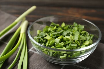 Cut fresh green onions in bowl on table, closeup