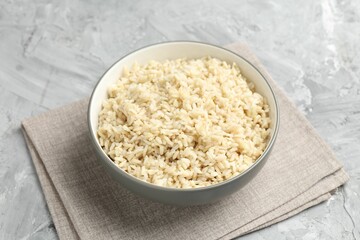 Delicious brown rice served on grey textured table, closeup