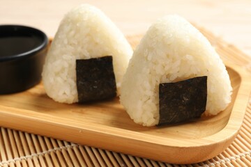 Rice balls (onigiri) and soy sauce on table, closeup. Traditional Japanese dish
