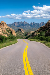 Naklejka premium Winding asphalt road through desert mountain range under a vibrant blue sky