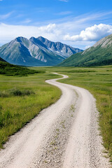 Winding dirt road through a green valley towards majestic mountains under a blue sky