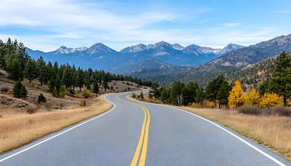 Naklejka premium Winding mountain road with autumn foliage and snow-capped peaks