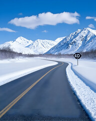 Winding snowy road through majestic mountains under a clear blue sky