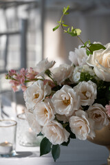 Creamy white roses and blush blooms in a soft-lit floral centerpiece