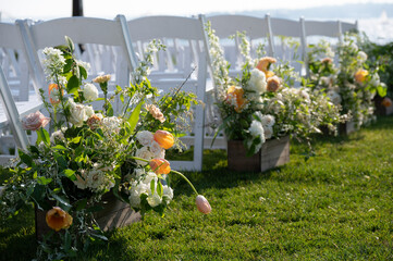 Outdoor wedding aisle with floral arrangements and white ceremony chairs