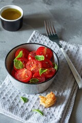 Salad of fresh cherry tomatoes with croutons, basil leaves, spices and aromatic olive oil on a gray background. Panzanella is a Tuscan vegetable salad popular in the summer. Italian Cuisine.
