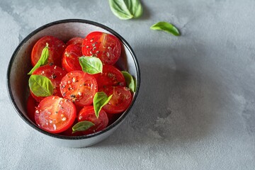 Salad of fresh cherry tomatoes with croutons, basil leaves, spices and aromatic olive oil on a gray background. Panzanella is a Tuscan vegetable salad popular in the summer. Italian Cuisine.
